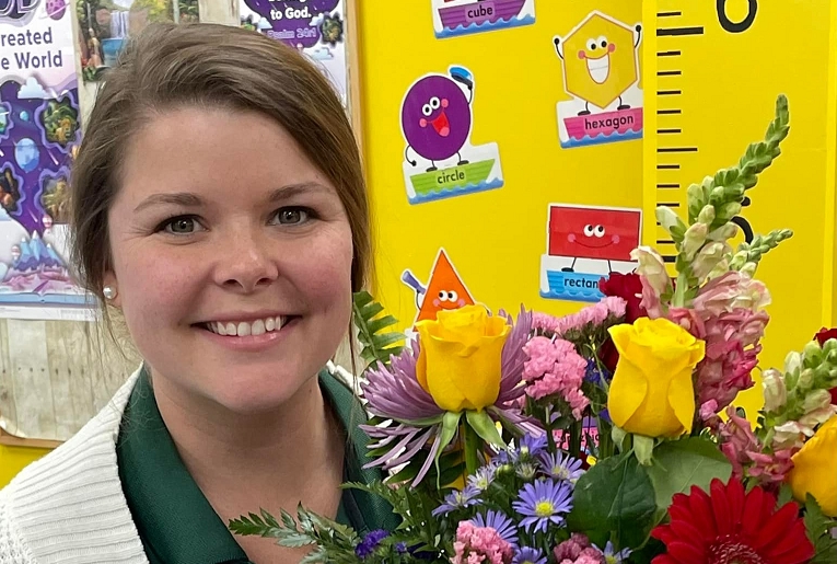 Teacher Megan Patterson smiling holding a bouquet of flowers